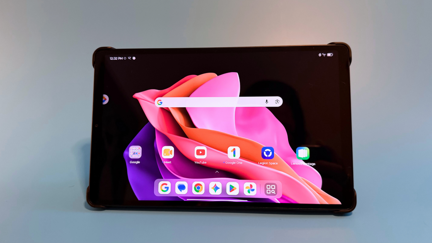 Lenovo Legion Tab Gen 5 đặt ngang trong bao gập, màn hình mở giao diện thư viện game với các bìa Assassin’s Creed, The Witcher 3 và NieR:Automata.