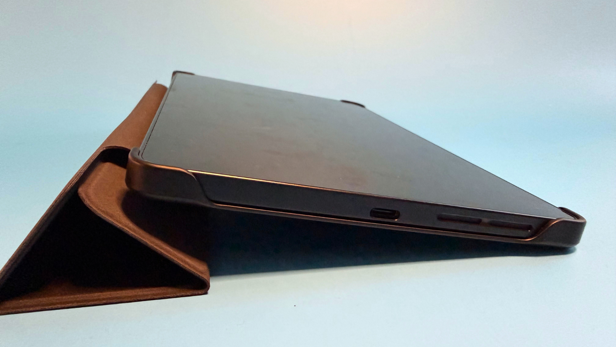 Góc thấp ở cạnh dưới Legion Tab Gen 5 khi máy dựng trên folio, thấy cổng USB-C, lưới loa và thân máy mỏng.