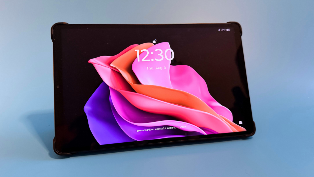 Lenovo Legion Tab Gen 5 đặt ngang trong bao gập màu đen, màn hình khóa hồng tím hiển thị 12:30 trên nền xanh.