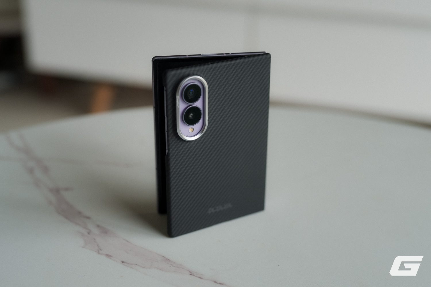 Ốp PITAKA vân sợi được cầm riêng, lộ lỗ khoét cụm camera.