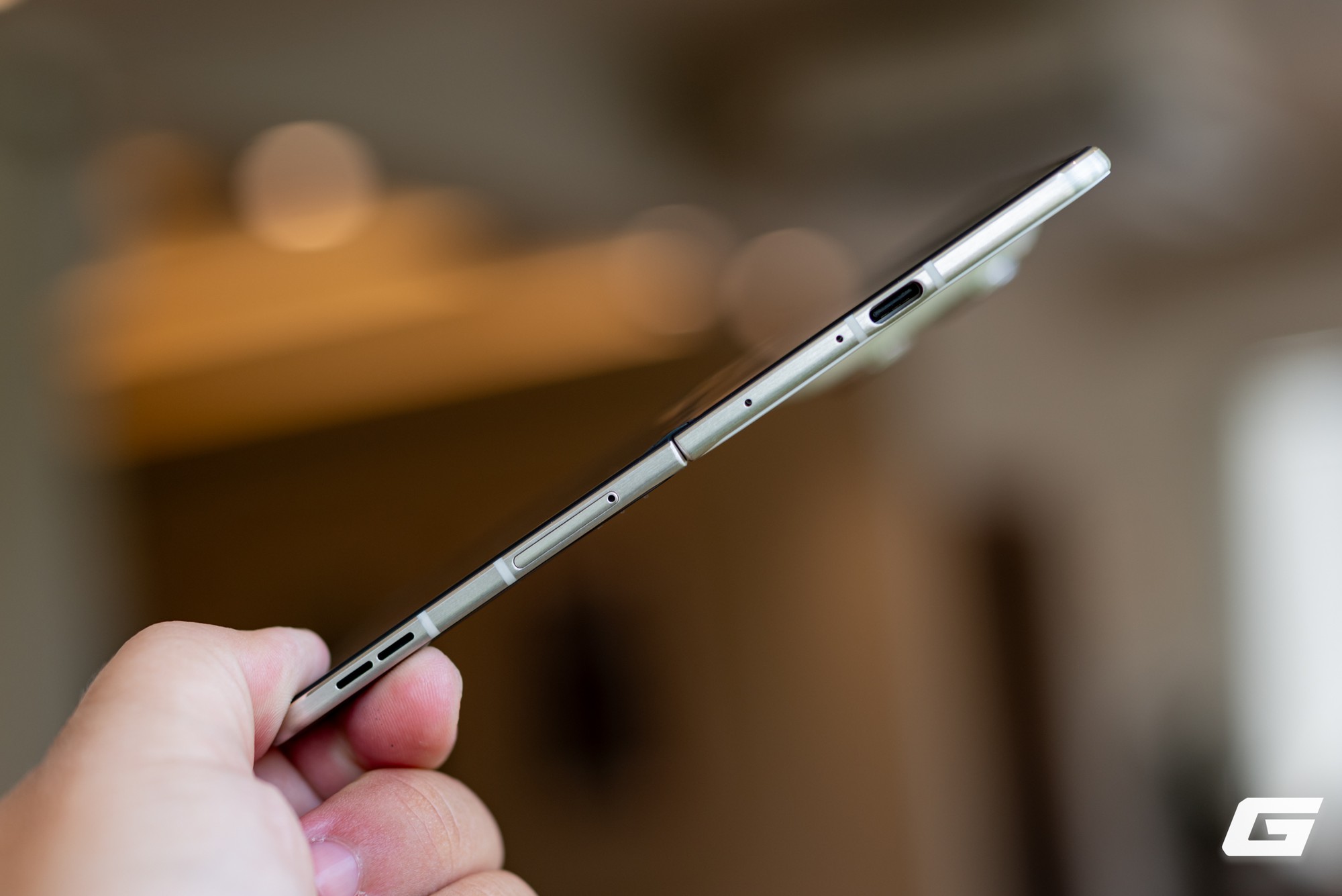 Người dùng cầm Razr Fold mở gần phẳng, thấy bản lề, cổng USB-C và cạnh dưới.