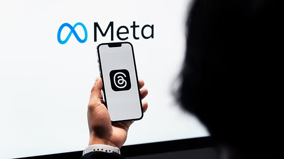 Một người cầm điện thoại trước logo Meta; ảnh minh họa bối cảnh sử dụng nền tảng Meta. Ảnh: GenK