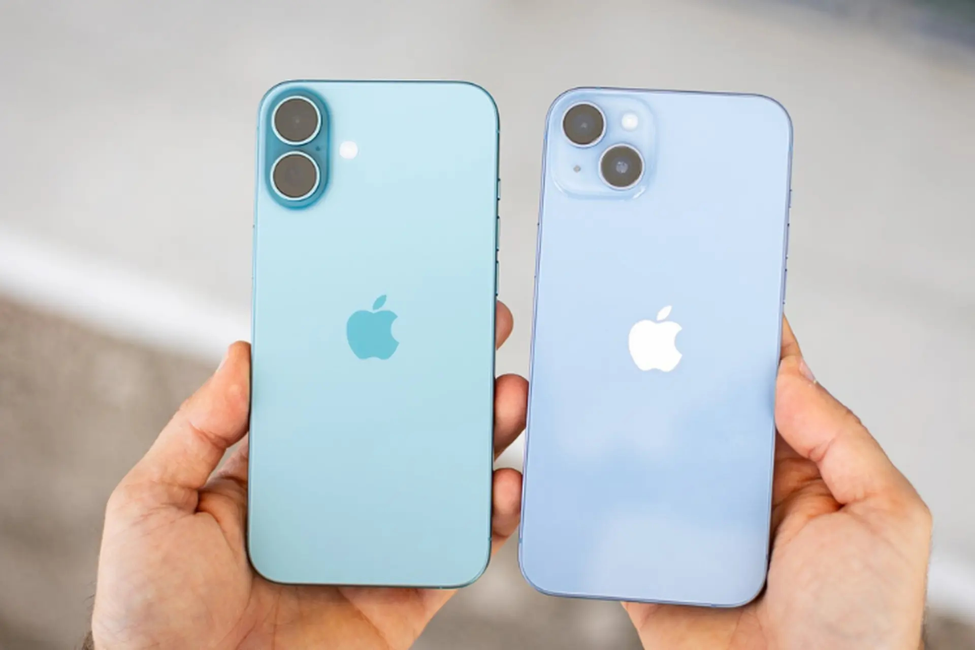 Hai iPhone màu xanh nhạt được cầm trên tay, lộ rõ khác biệt cụm camera