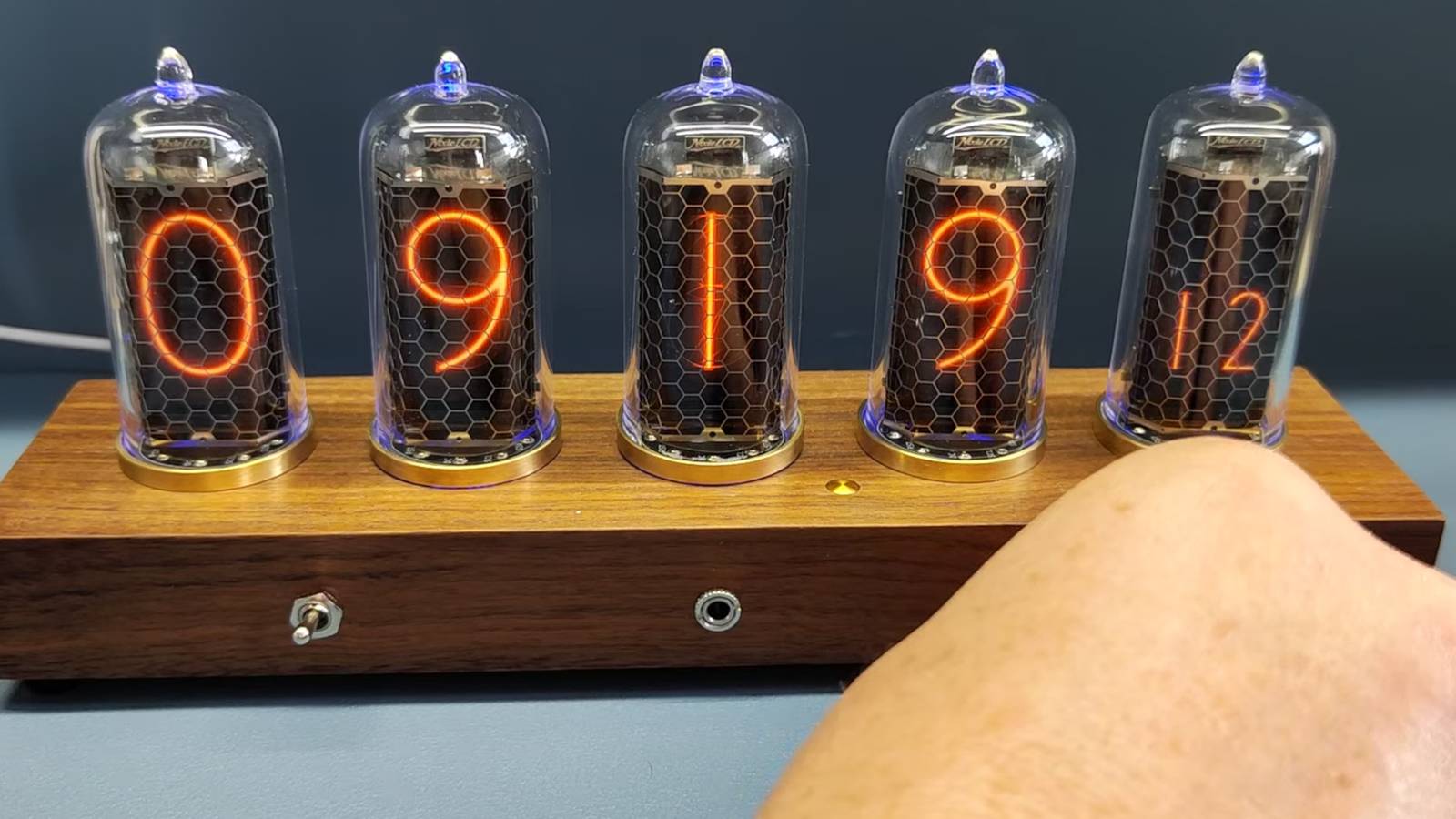 Đồng hồ ống Nixie với năm chữ số phát sáng trên đế gỗ
