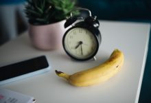 Smartphone và đồng hồ báo thức trên bàn làm việc buổi sáng
