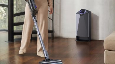 Người dùng đang điều khiển máy hút bụi Narwal V50 Cube với đèn soi bụi trên sàn gỗ cạnh trạm sạc