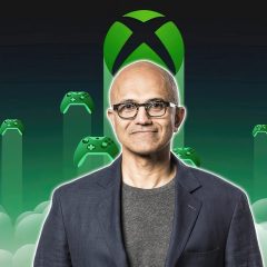Satya Nadella đứng trước biểu tượng Xbox và các tay cầm chơi game