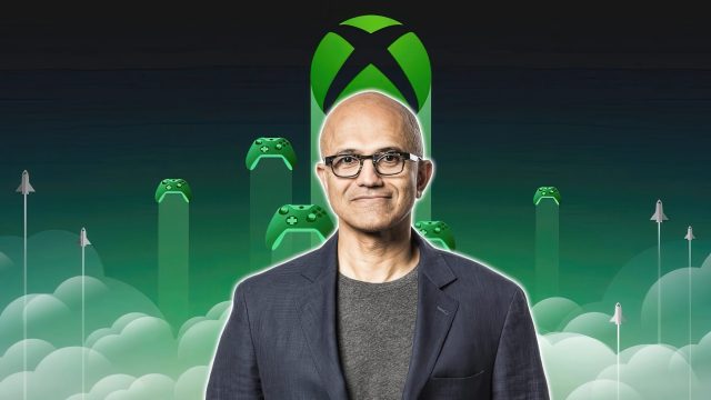 Satya Nadella đứng trước biểu tượng Xbox và các tay cầm chơi game