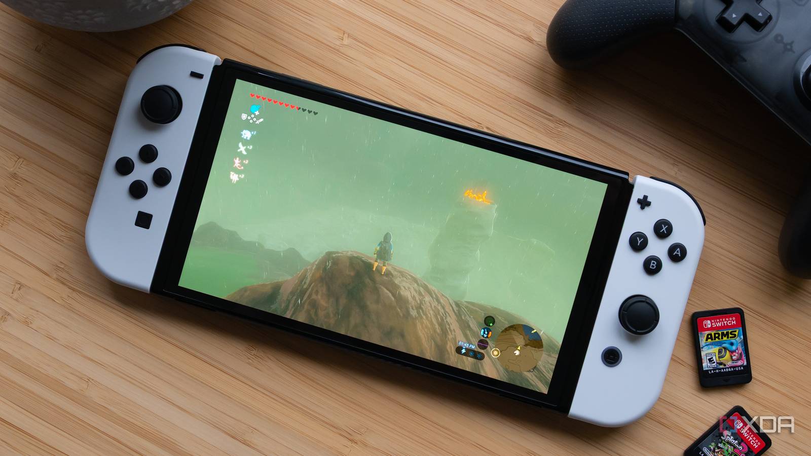 Máy Nintendo Switch OLED đặt trên bàn gỗ cạnh băng game chính hãng Nintendo Switch Sports