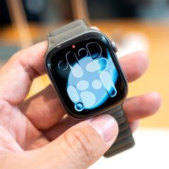 Apple Watch được cầm trên tay với mặt đồng hồ màu xanh