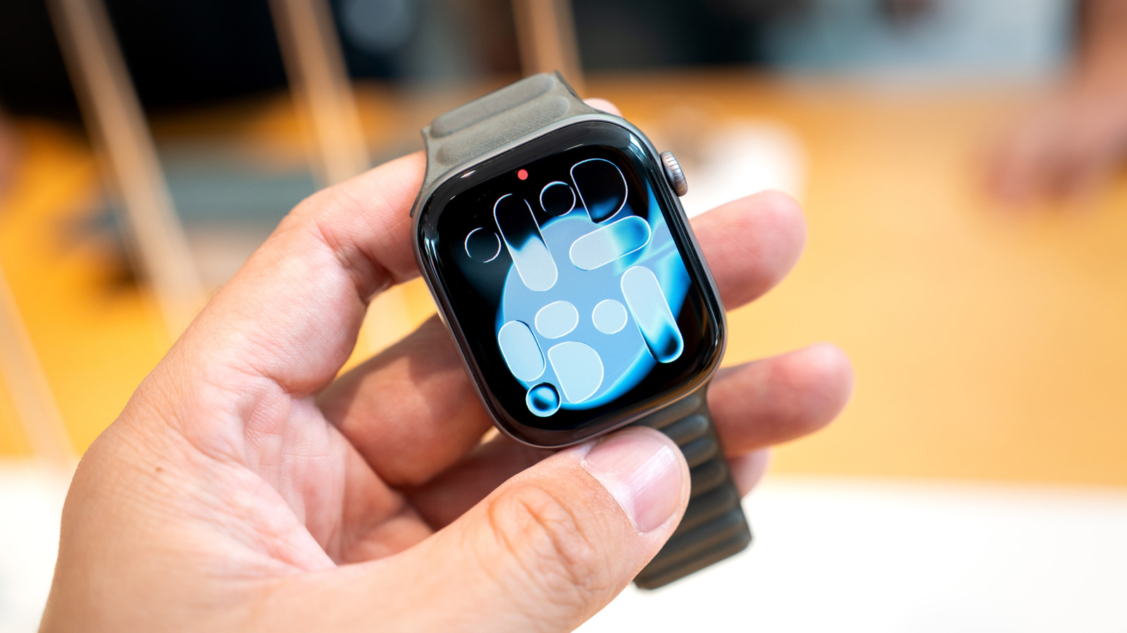 Apple Watch được cầm trên tay với mặt đồng hồ màu xanh