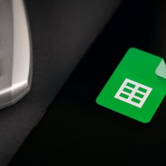 Biểu tượng Google Sheets trên điện thoại cạnh máy tính cầm tay