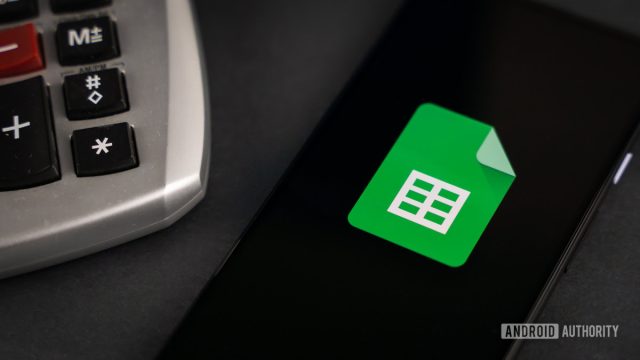 Biểu tượng Google Sheets trên điện thoại cạnh máy tính cầm tay
