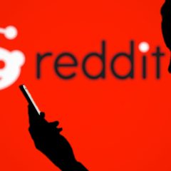 Bóng người dùng smartphone trước logo Reddit màu đỏ