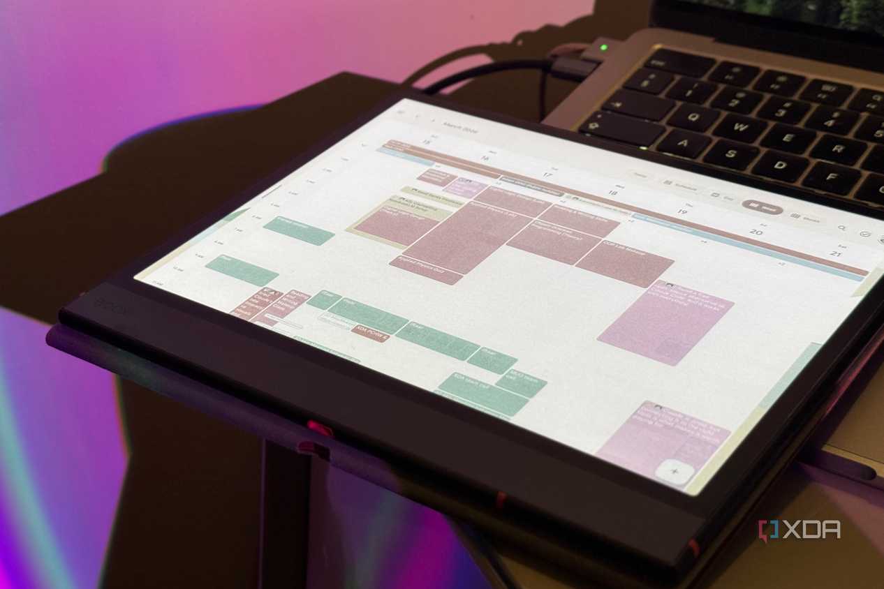 Boox tablet in a folio case showing Google Calendar in front of a MacBook keyboard
