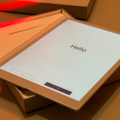 Boox tablet in its open box showing the Hello setup screen under orange light