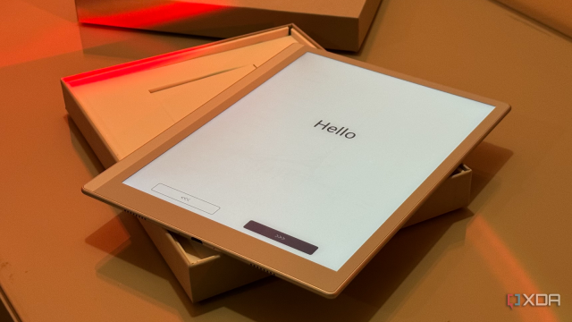 Boox tablet in its open box showing the Hello setup screen under orange light