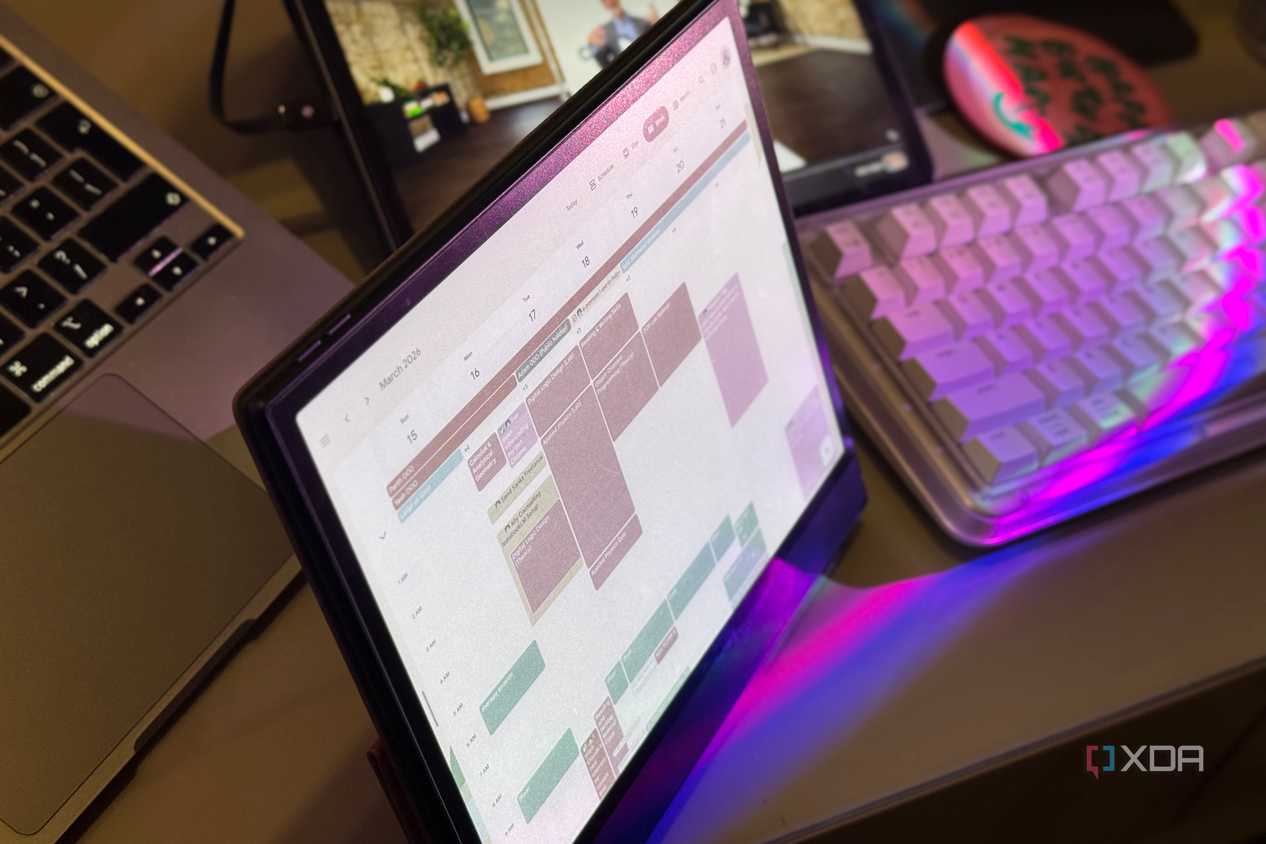 Boox tablet showing Google Calendar between a MacBook and a purple mechanical keyboard