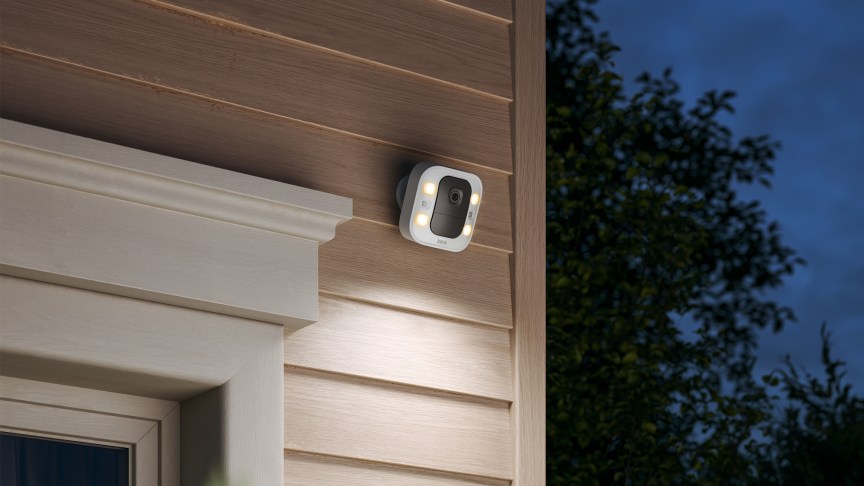 Camera đèn rọi Blink gắn trên tường ngoài nhà vào ban đêm.