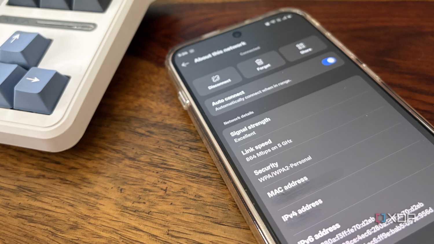 Close-up of a smartphone on a brown desk showing details of a Wi-Fi network