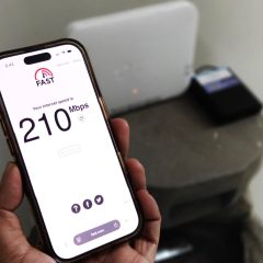 Close-up of a smartphone showing an internet speed test with a router in the background