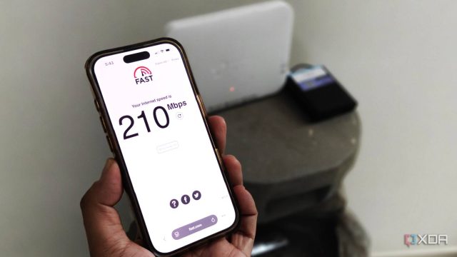 Close-up of a smartphone showing an internet speed test with a router in the background