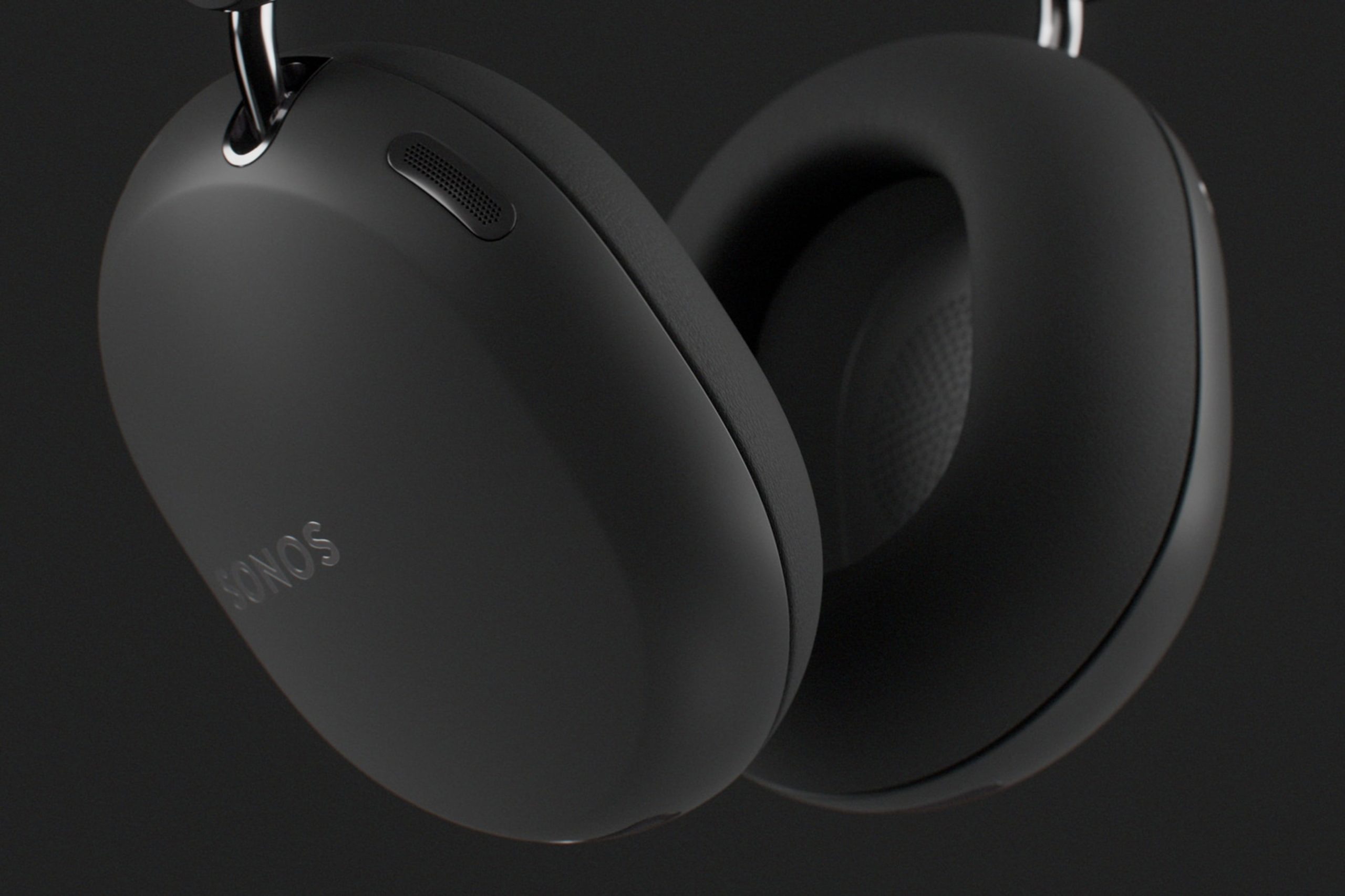 Closeup of the ear cups on a pair of black Sonos Ace Ultra headphones on a dark grey background