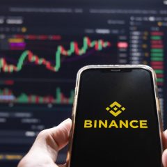 Điện thoại hiển thị Binance trước biểu đồ giá tiền mã hóa