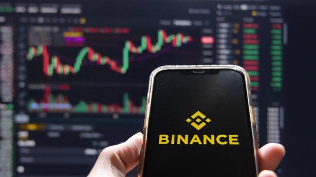 Điện thoại hiển thị Binance trước biểu đồ giá tiền mã hóa