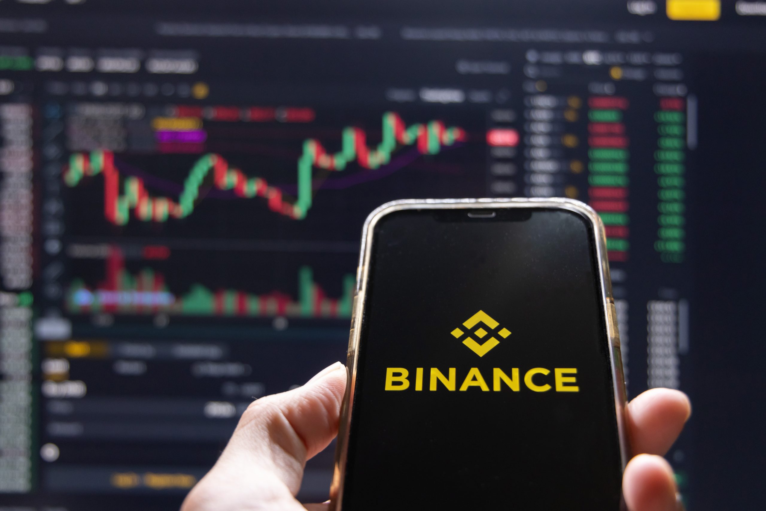 Điện thoại hiển thị Binance trước biểu đồ giá tiền mã hóa