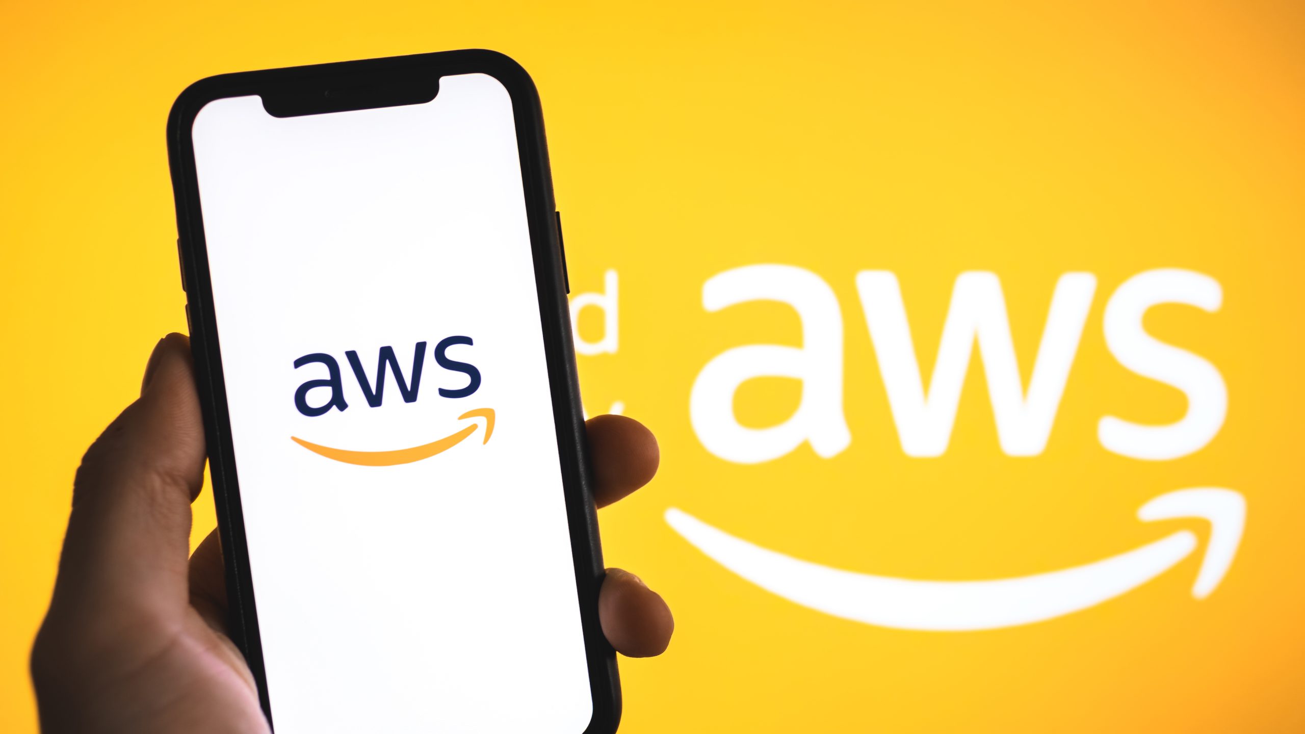 Điện thoại hiển thị logo AWS trước nền màu cam có logo AWS