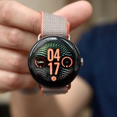 Đồng hồ Pixel Watch mặt tròn, dây vải được cầm trước máy ảnh