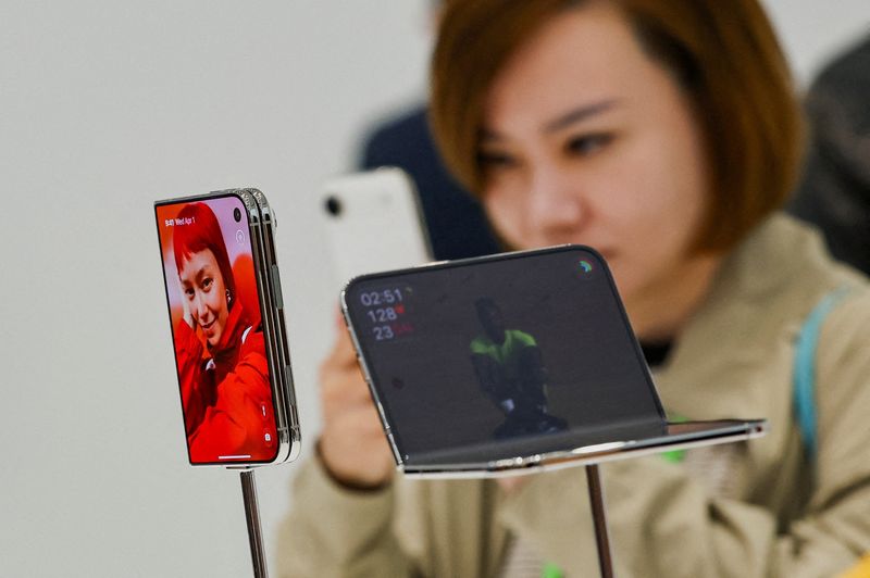 Hai máy iPhone Duo trên giá trưng bày, một người đang cầm điện thoại khác phía sau