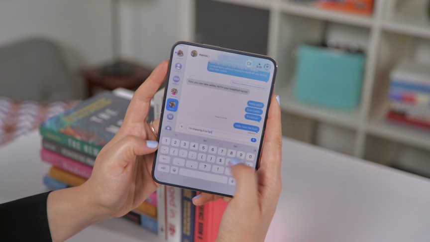 Hai tay thao tác ứng dụng nhắn tin trên iPhone Duo