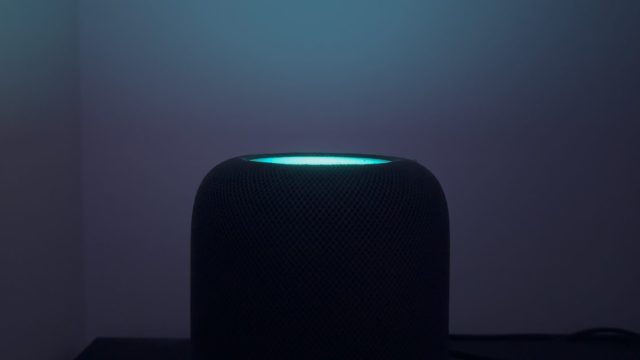 HomePod mini phát sáng màu xanh trên mặt cảm ứng trong phòng tối