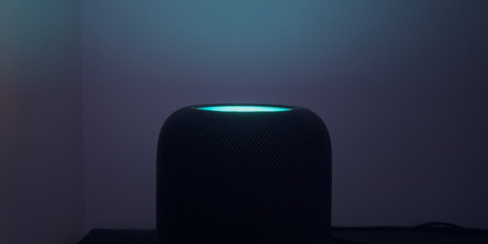 HomePod mini phát sáng màu xanh trên mặt cảm ứng trong phòng tối