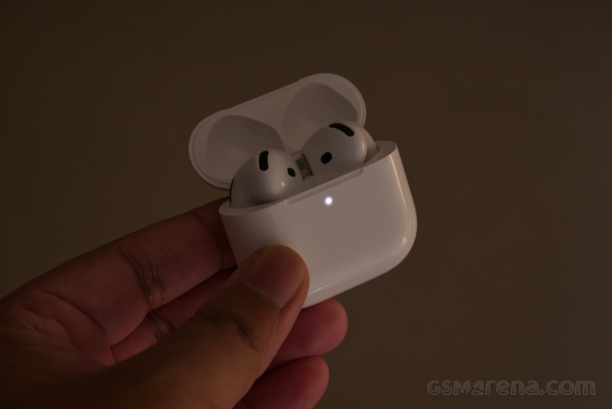 Hộp sạc AirPods 5 mở trong phòng tối với đèn báo sáng