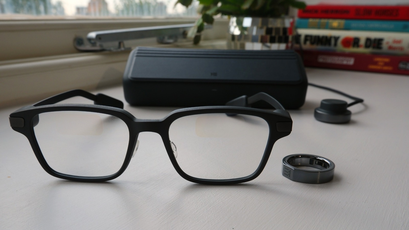 Kính Even Realities G2, hộp sạc và nhẫn R1 trên mặt bàn