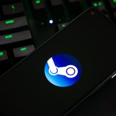 Logo Steam trên màn hình điện thoại cạnh bàn phím máy tính