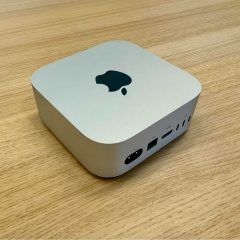 Mac mini màu bạc đặt trên bàn gỗ, thấy mặt sau có cổng HDMI và Thunderbolt