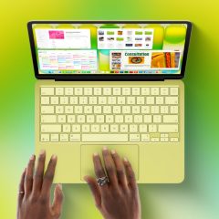 MacBook Neo màu vàng, nhìn từ trên xuống khi có người đang sử dụng bàn di chuột