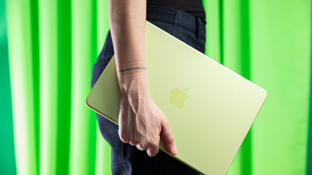 MacBook Neo màu xanh cầm bên mình