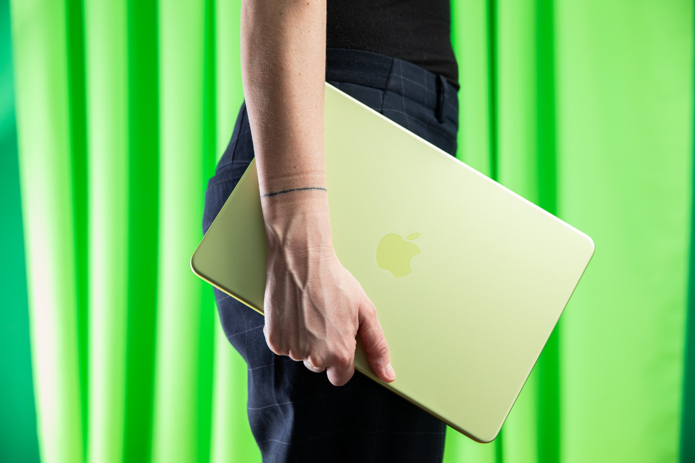 MacBook Neo màu xanh cầm bên mình
