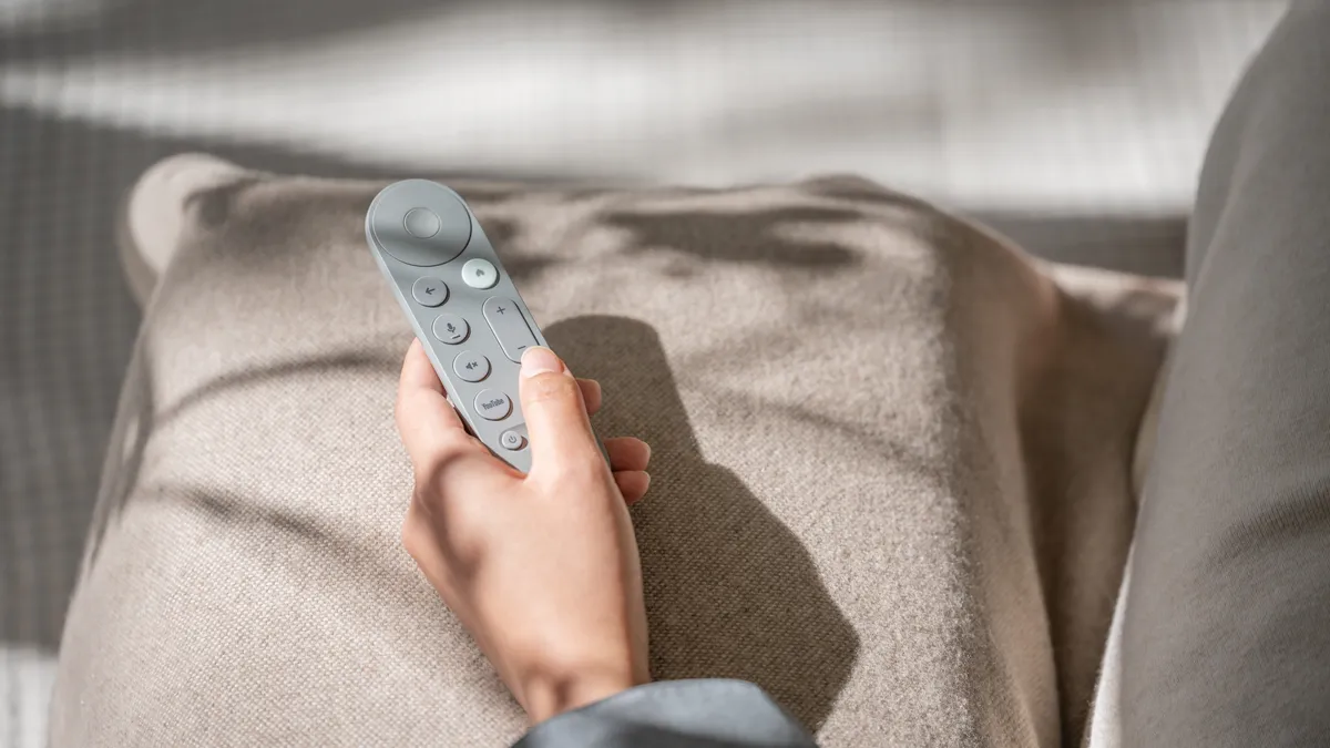Người dùng cầm điều khiển Google TV Streamer