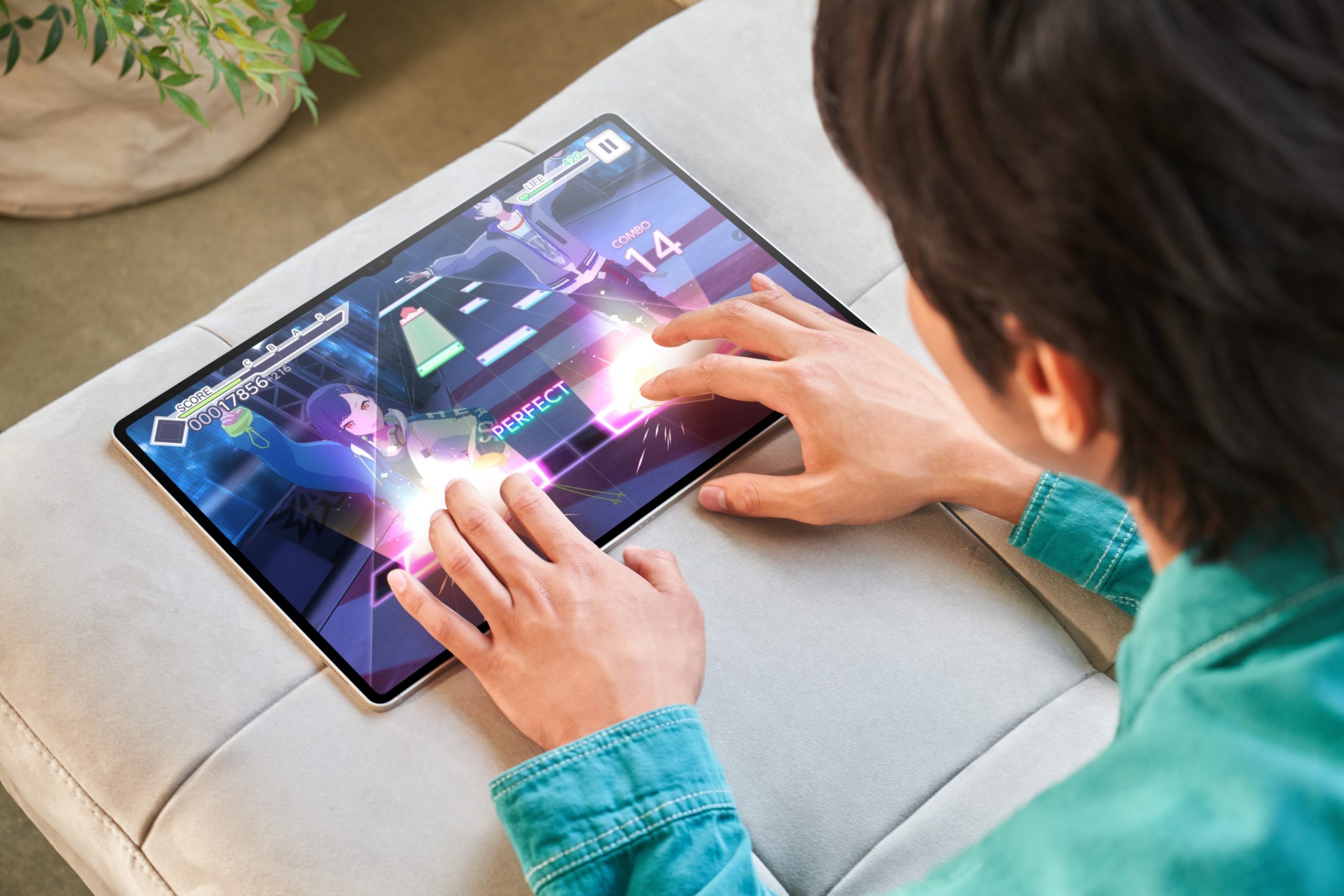 Người dùng chơi game nhịp độ cao trên Galaxy Tab S9 đặt trên ghế sofa