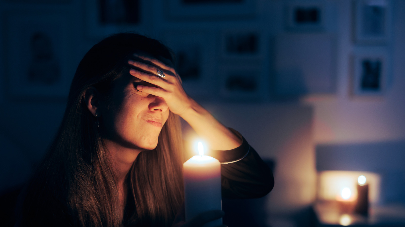 Người phụ nữ vỗ trán khi cầm nến trong căn phòng tối