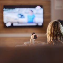 Người xem cầm điều khiển trước TV trong phòng khách