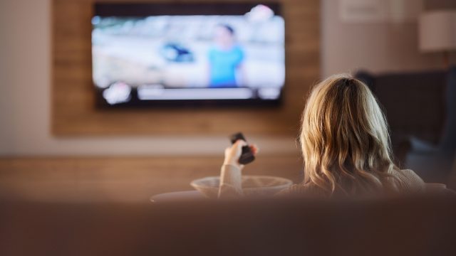 Người xem cầm điều khiển trước TV trong phòng khách