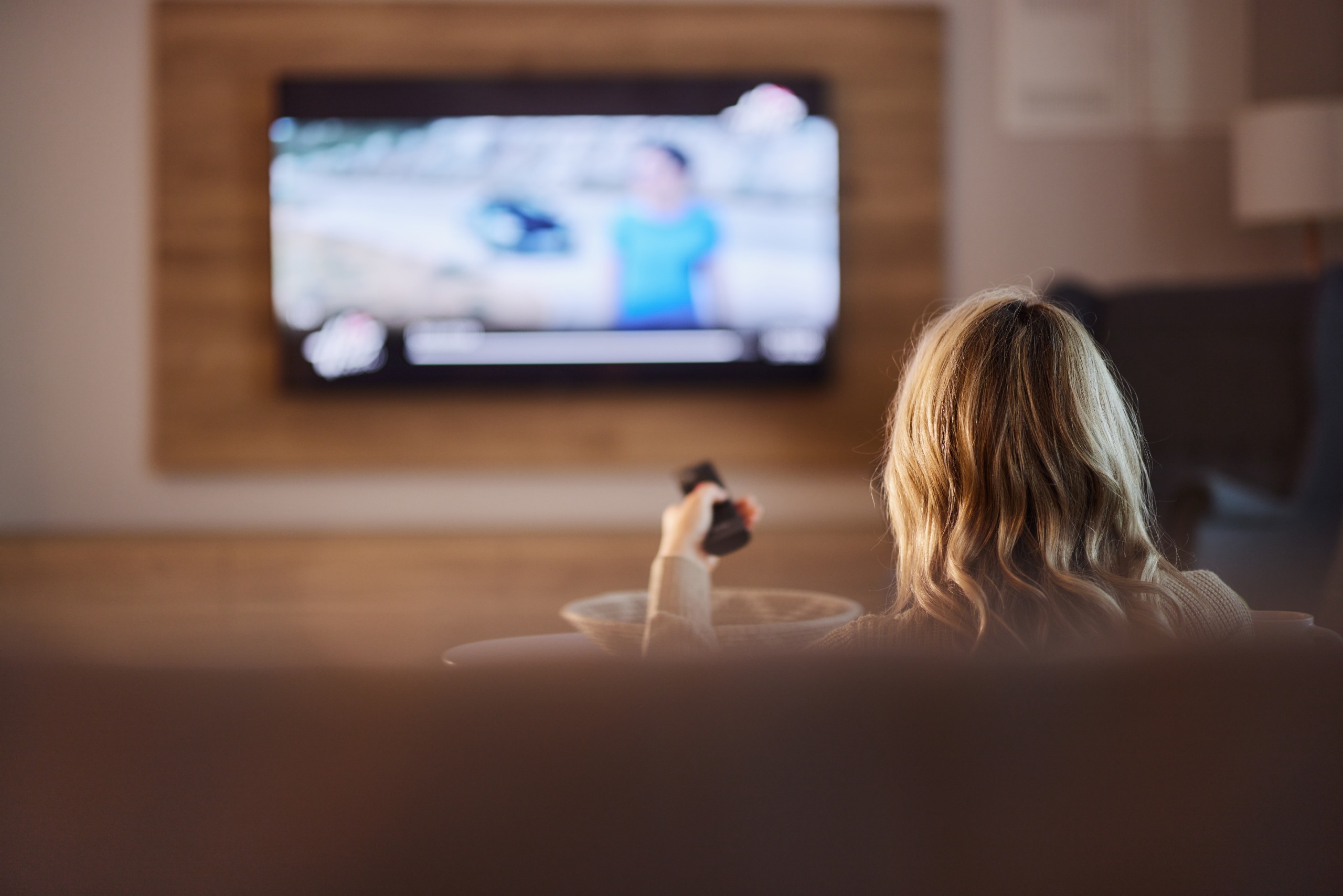 Người xem cầm điều khiển trước TV trong phòng khách
