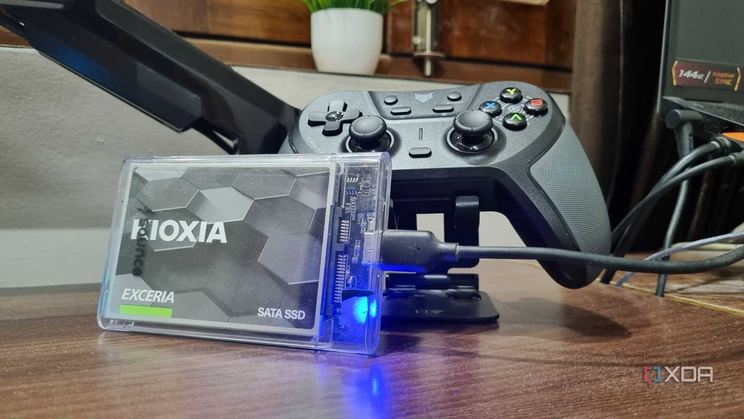 Ổ SSD SATA trong hộp chuyển kết nối USB bên cạnh tay cầm chơi game